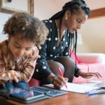 Kid using a tablet while their mom is working. 